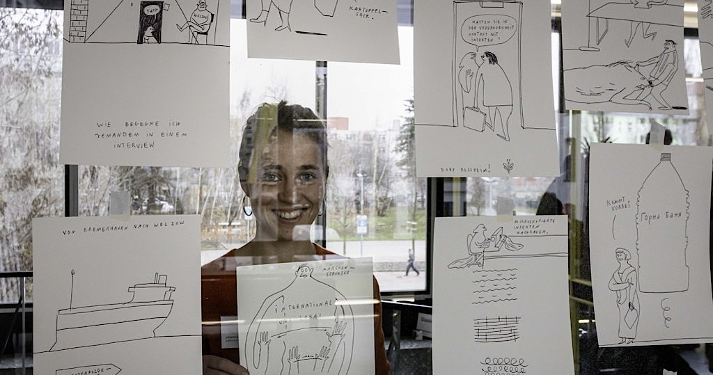 Die Illustratorin Johanna Benz hinter einer Glasscheibe, an der Zeichnungen von ihr kleben (Foto: Jörg Farys)