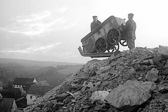 Schwarz-Weiß-Fotografie von 1909, auf der zwei Bergleute mit einem Auslaufhunt zu sehen sind.